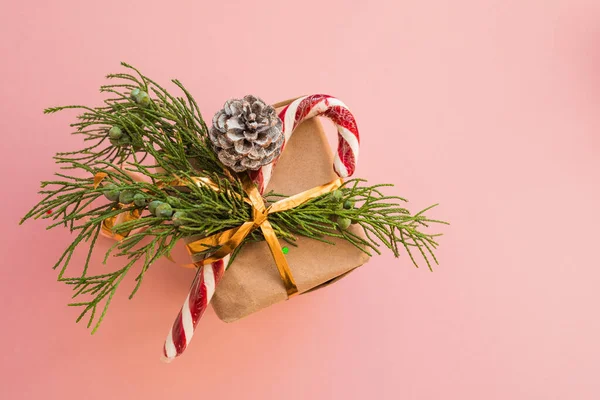 用杉木枝条做的牛皮纸和粉色背景的棒棒糖做的圣诞礼物 配上五颜六色的糖果 并附有文字圣诞概念 — 图库照片