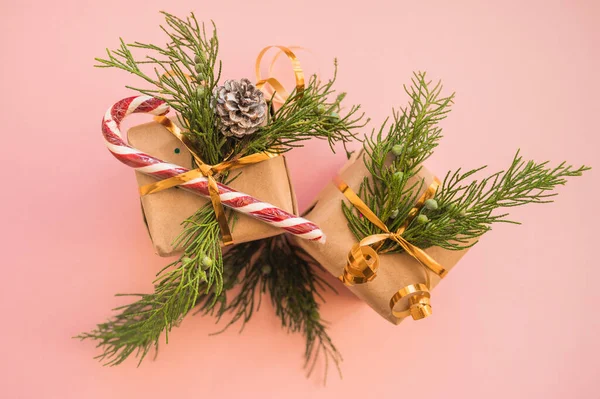 クリスマスギフトでクラフト紙でモミの枝とロリポップピンクの背景にマルチカラーキャンディで場所とテキストクリスマスのコンセプト — ストック写真