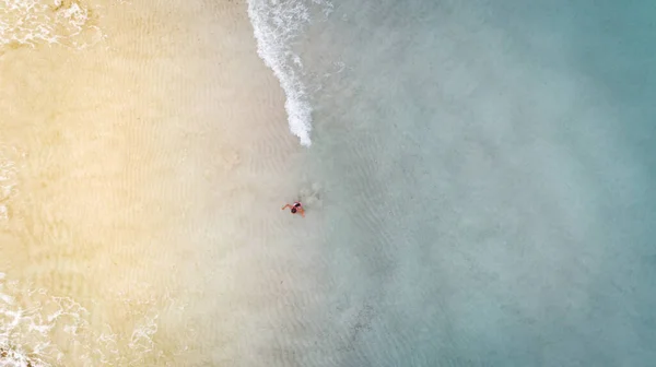 ドローンで空から見た黄色い砂と青い水の間の小さな女の子 — ストック写真