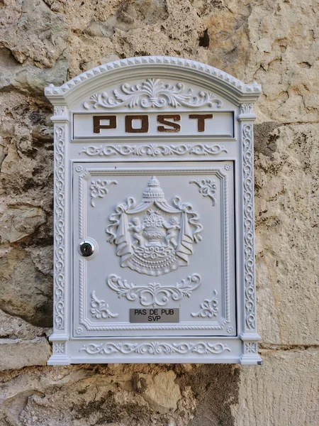 Mail box, old white post box on a stone wall in a medieval village, France.