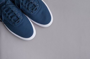 Gri arka planda beyaz tabanlı mavi tekstil ayakkabıları. Düz yatıyordu