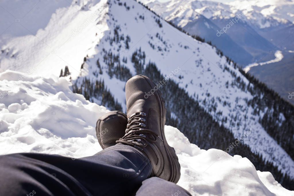 Sitting on top of a mountain cover in snow, winter boots help keep the feet warm. 