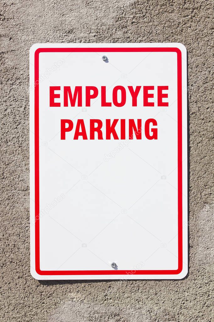 Employee parking sign with copy space hangs on a concrete wall. 
