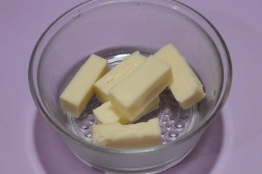 Cam kasedeki tereyağı parçaları siyah arka planda izole edilmiş.