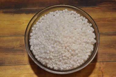 Beyaz sago incileri ya da sabudana çiğ sago topları ahşap kasede izole edilmiş.