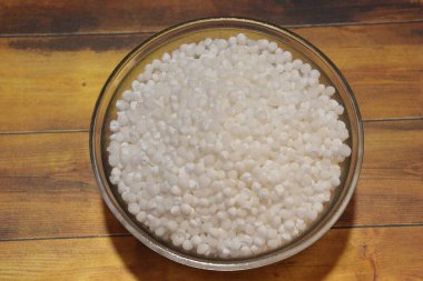 Beyaz sago incileri ya da sabudana çiğ sago topları ahşap kasede izole edilmiş.