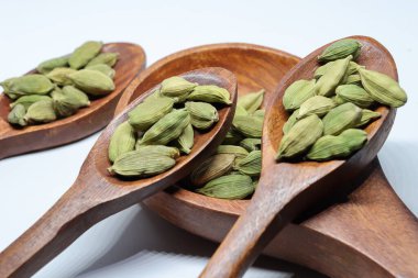 Beyaz arkaplanda izole edilmiş küçük yeşil kardamon tohumu yığını