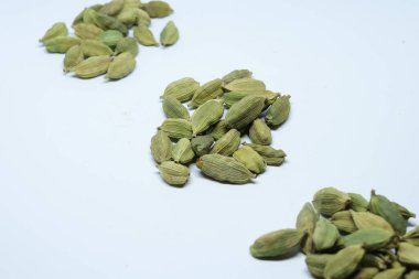 Beyaz arkaplanda izole edilmiş küçük yeşil kardamon tohumu yığını