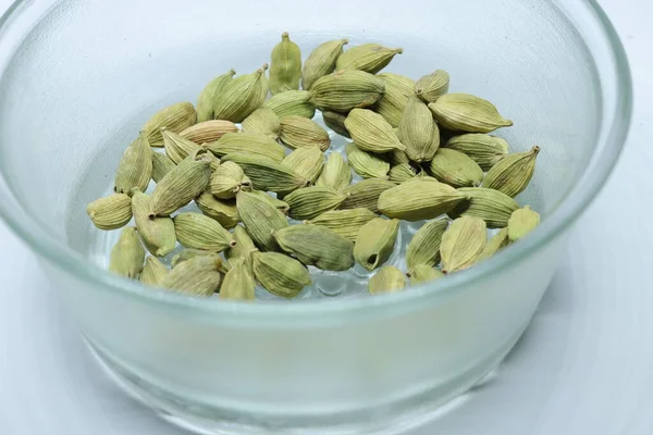 Beyaz arka planda izole edilmiş yeşil kakule tohumları.