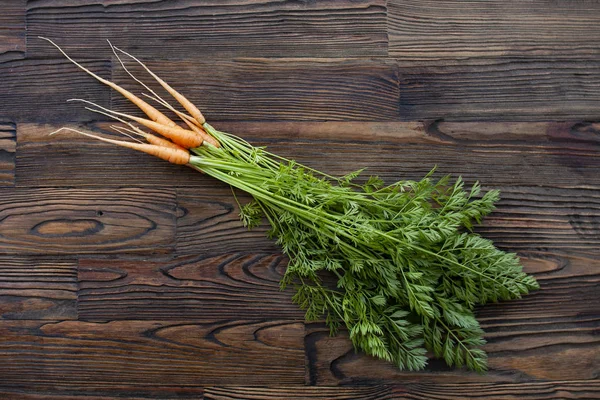 一串胡萝卜与叶子在棕色木制背景 为烹饪食谱 素食食品性质 — 图库照片