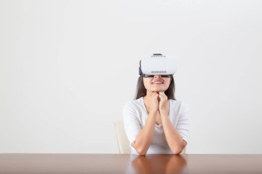 Beyaz arkaplan üzerine sanal gerçeklik gözlüğü takan genç bir kadın oyunculuk yapıyor.