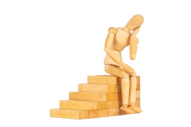 Tahta kukla, beyaz arka planda izole edilmiş merdivenleri geliştirmek için tahta blokların üzerinde oturuyor. Ekonomik zehirlenme konsepti yüzünden stresli.
