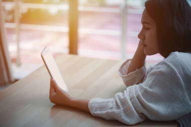 Genç Asyalı kadın tabletle ilgili makaleyi tutuyor ve okuyor..