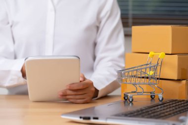 Kadın satıcı tablet kullanılarak sipariş edilen ürünlerin sayısını kontrol ediyor. Çevrimiçi Alışveriş ve E-ticaret kavramı.