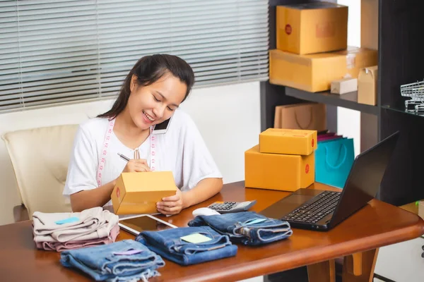 Ürünlerini online alışveriş yoluyla sipariş eden müşterilere, tüketicilerin doğrudan internet konseptinden alışveriş yapmasına olanak sağlayan Elektronik ticaret modeline teslimat hazırlığı için paket kutusunun önüne kadın satıcı adresi.