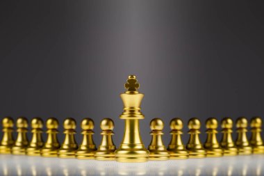 Satrancın altın kralı arkasında duran piyon sürüsünün önünde duruyor. Liderlik kavramı ve iş rekabetinde başarı.