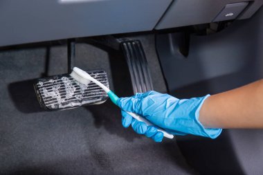 Elin lastik eldiven takıyor ve fırça kullanarak fren pedalını temizliyorsun. Araba temizleme konsepti.