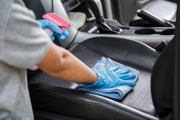 Hand wearing rubber gloves and using a blue microfiber cloth clean the car interior. Cleaning car  interior concept.