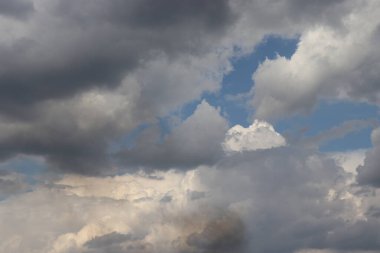 Mavi gökyüzünde beyaz ve gri bulutlar, bulutların arka planında gri bir duman bulutu