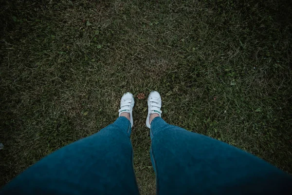 Top view girl long legswhite sneakers on the grass — Stock Photo, Image