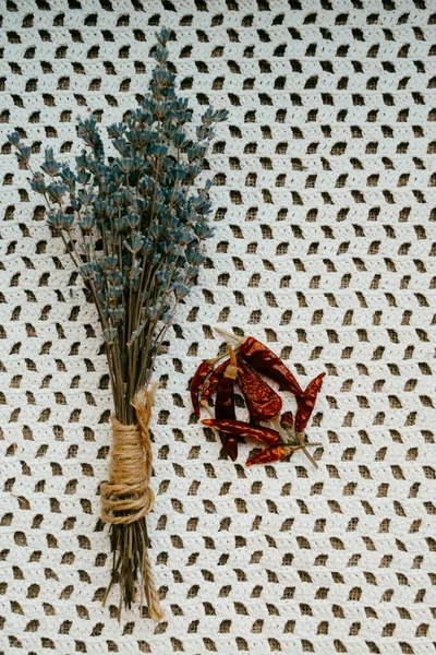 Trockene Chilischoten und Lavendel auf weißer gehäkelter Tischdecke — Stockfoto