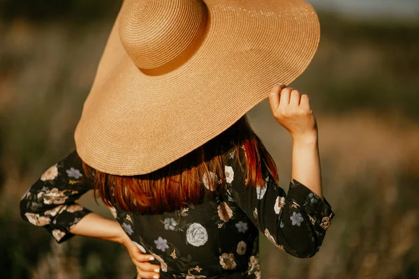 Jonge vrouw met een zomer grote stro hoed in het veld — Stockfoto