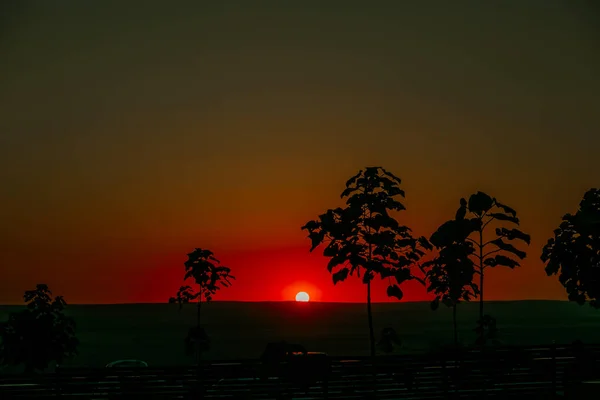 Leuchtend orangefarbene Sonne am Abend versteckt sich hinter Hügel — Stockfoto