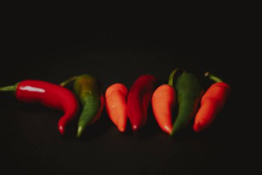 Siyah arkaplanda kırmızı turuncu ve yeşil biber demeti