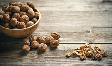 Taze ceviz çekirdekleri ve eski ahşap masadaki bir kasenin içindeki cevizler. Sağlıklı organik yiyecekler, biyoviands, doğal arka plan. Reklam metniniz için alanı kopyalayın.