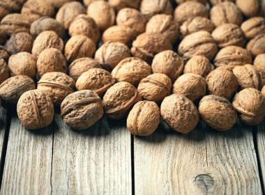 Tahta masadaki ceviz yığını, doğal desenli arka plan detayı. Ceviz kabuğunun kahverengi yüzey dokusunu kapat. Sağlıklı organik yiyecekler, BIO virüsleri, doğa konseptine dönüş. Boşluğu kopyala.