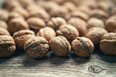 Tahta masadaki ceviz yığını, doğal desenli arka plan detayı. Ceviz kabuğunun kahverengi yüzey dokusunu kapat. Sağlıklı organik yiyecekler, BIO virüsleri, doğa konseptine dönüş. Boşluğu kopyala.