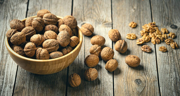 Свежие ореховые ядра и целые грецкие орехи в миске на деревенском старом деревянном столе. Здоровые органические продукты питания, BIO viands, природный фон. Скопируйте место для вашего рекламного сообщения.