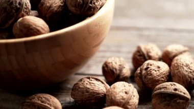 Taze ceviz çekirdekleri ve 4K VIDEO 'daki eski ahşap masada bir kasenin içindeki cevizler. Sağlıklı organik gıda, BIO videoları, doğal arka plan konsepti..