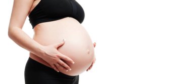 Ayakta duran ve çıplak karnıyla dokunan hamile bir kadın. Beyaz arka planda izole edilmiş. Bebek beklentisi. Aşk, mutluluk ve güvenlik kavramı. Yakın plan..