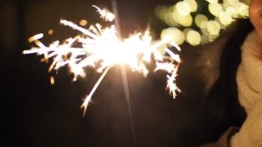 SLOW MOTION HD VIDEO 'da bulanık Noel ışıklarıyla yanan maytap. Geceleyin soyut arka plan dekorasyonunda parlayan ve ışıldayan yıldızlara yaklaş. Yarı hız.