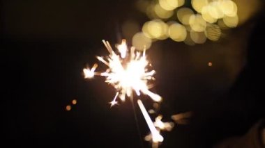 SLOW MOTION HD VIDEO 'da bulanık Noel ışıklarıyla yanan maytap. Geceleyin soyut arka plan dekorasyonunda parlayan ve ışıldayan yıldızlara yaklaş. Yarı hız.