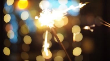 SLOW MOTION HD VIDEO 'da bulanık Noel ışıklarıyla yanan maytap. Geceleyin soyut arka plan dekorasyonunda parlayan ve ışıldayan yıldızlara yaklaş. Yarı hız.