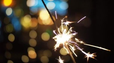 SLOW MOTION HD VIDEO 'da bulanık Noel ışıklarıyla yanan maytap. Geceleyin soyut arka plan dekorasyonunda parlayan ve ışıldayan yıldızlara yaklaş. Yarı hız.