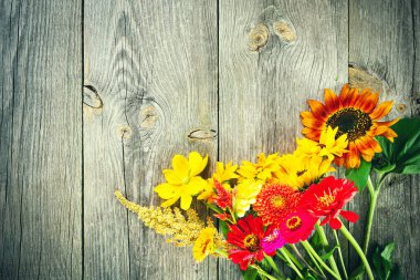 Tatil sonbahar buketi. Eski ahşap arka planda düzenlenmiş renkli çiçek çerçevesi. Reklam metniniz veya tanıtım içeriğiniz için üst görünüm ve kopyalama alanı.