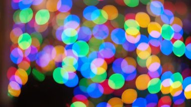 HD VIDEO 'da gece karanlığında bulanık ve parlayan Noel ışıkları süslemesi. Odak dışında soyut dairesel bokeh.