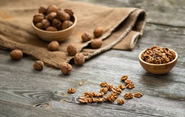 Taze ceviz çekirdekleri ve eski ahşap masadaki bir kasenin içindeki cevizler. Sağlıklı organik yiyecekler, biyoviands, doğal arka plan. Reklam metniniz için alanı kopyalayın.