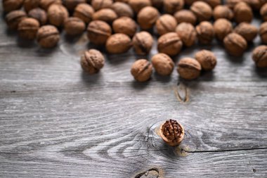 Bir yığın ceviz ve ahşap masada bir ceviz çekirdeği. Doğal desenli arka plan detayı. Kahverengi yüzey dokusunu kapat. Sağlıklı organik gıda, BIO viands, doğa konseptine dönüş..