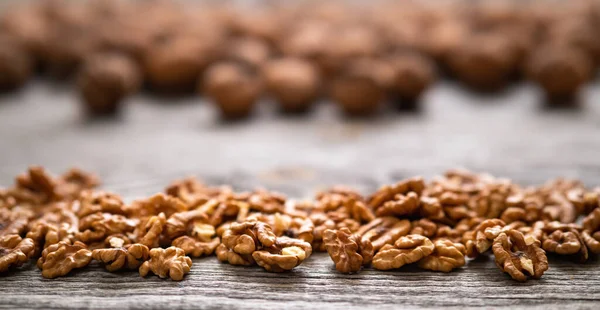 Bir yığın taze ceviz çekirdeği ve ahşap masa üzerinde ceviz, doğal desenli arka plan detayı. Kahverengi yüzey dokusunu kapat. Sağlıklı organik gıda, BIO viands, doğa konseptine dönüş..