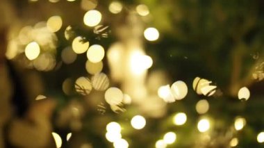 SLOW Motion HD VIDEO 'da ışıklandırılmış Noel ağacı ile cep telefonuyla mesajlaşan güzel bir kız. Arka planda parlak, bulanık ışıklar var. Yakın plan. Yarı Hız.