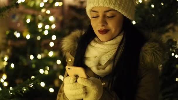 Prachtig Lachend Meisje Sms Met Mobiele Telefoon Door Verlichte Kerstboom — Stockvideo