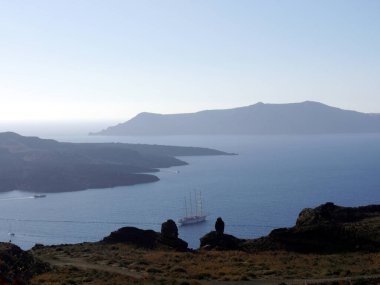 Yunanistan 'ın Santorini adasındaki Fira yakınlarındaki bir körfezde lüks yolcu gemileri. Gün batımında Akdeniz, adalar ve kalderanın manzarası.