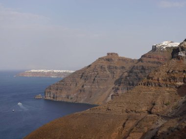 Yunanistan 'ın Santorini adasındaki Fira kasabasından dağların, denizin ve doğanın panoramik manzarası. Kalderanın ve körfezdeki gemilerin görüntüsü..
