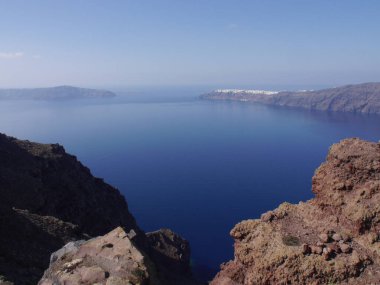 Yunanistan 'ın Santorini adasındaki Fira kasabasından dağların, denizin ve doğanın panoramik manzarası. Kalderanın ve körfezdeki gemilerin görüntüsü..