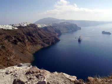 Yunanistan 'ın Santorini adasındaki Fira kasabasından dağların, denizin ve doğanın panoramik manzarası. Kalderanın ve körfezdeki gemilerin görüntüsü..