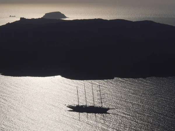 The silhouette of a luxury cruise ship in a bay near Fira. View of the mediterranean sea, islands and caldera during sunset.